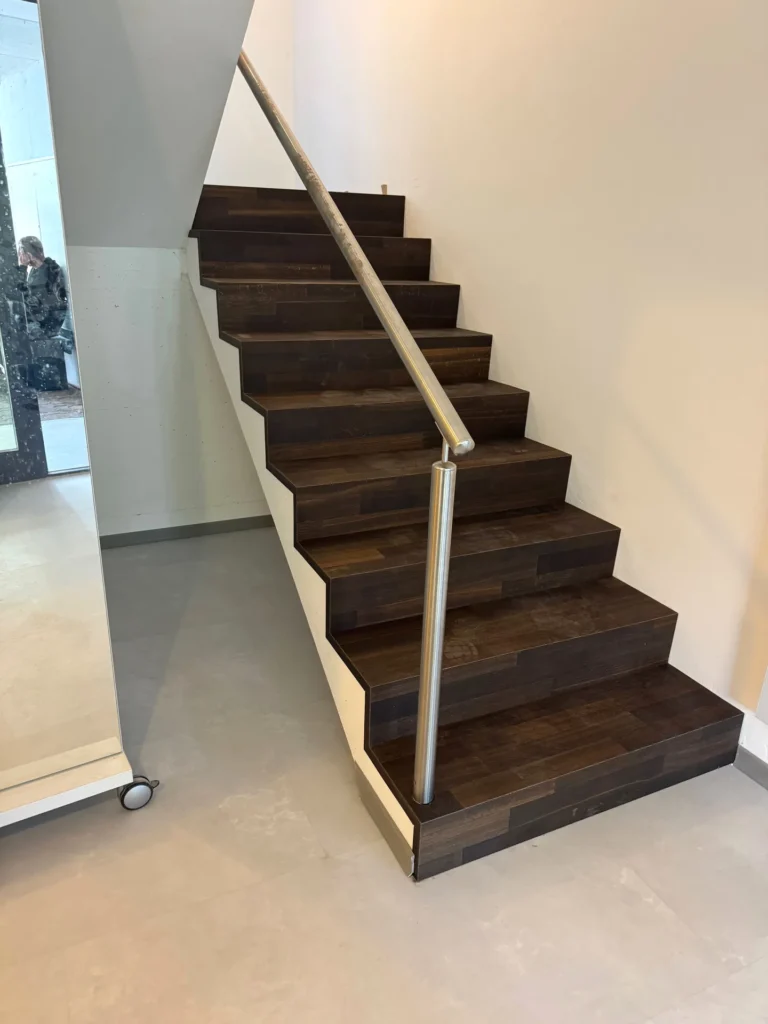 Treppe mit neuen dunklen Holzstufen und Edelstahl-Handlauf – BEMO Montagen Zürich